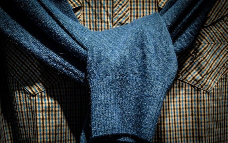 pull bleu noué autour d'une chemise à motifs