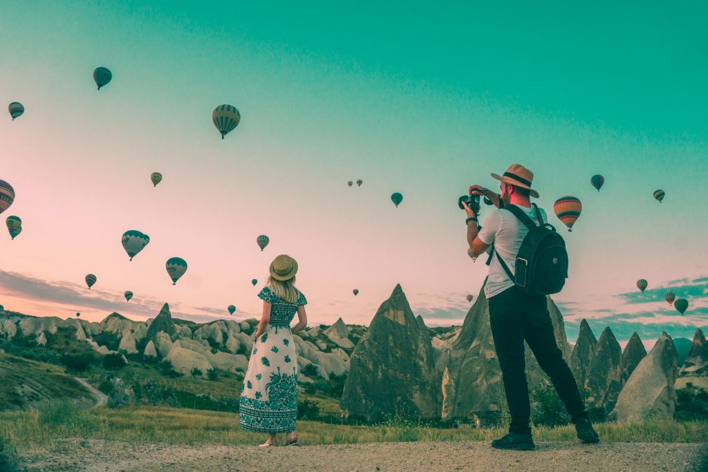 homme et femme prenant en photo des montgolfières